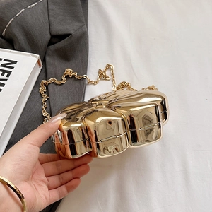 Detailed view of flower-shaped gold metal evening clutch with mirror finish and chain strap