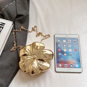 Macro shot of gold flower shaped metallic evening clutch bag with chain strap