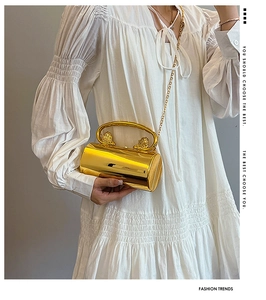 Detailansicht der goldenen Zylindertasche mit Löwenkopf-Griff und feiner Kette