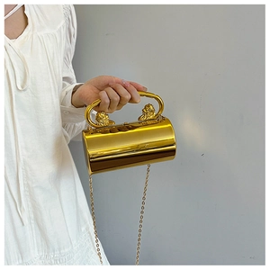 Detail der goldenen Zylindertasche mit verzierten Löwenkopfgriffen und Spiegeleffekt