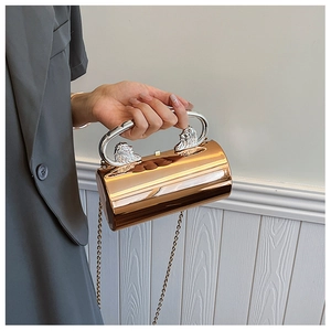 Detail der roségoldenen Zylinder-Clutch mit silbernem Löwenkopfgriff und Kette