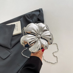 Macro detail of silver flower-shaped evening clutch with mirror finish and chain strap