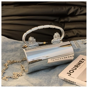 Details der silbernen Zylindertasche mit Löwenkopfgriffen und Kette auf Denim