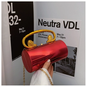Detail der roten zylindrischen Abendtasche mit goldener Löwenkopfprägung und U-förmigem Griff