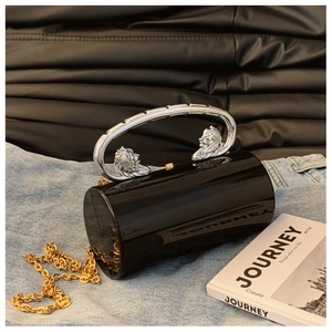 Detail der schwarzen zylindrischen Clutch mit Löwenkopf-Griff und goldener Metallkette