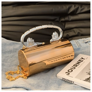 Detailaufnahme der goldenen Zylindertasche mit silbernem Löwenkopfgriff und Kette