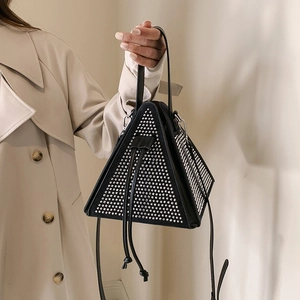 Sac à main triangulaire noir chic avec clous argentés et cordon, porté par un mannequin