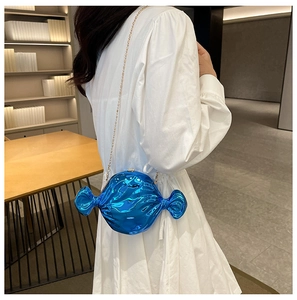 Detail of candy-shaped royal blue metallic clutch bag with golden chain on model
