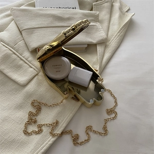 Golden acrylic shell crossbody bag with metal chain showing internal space and capacity