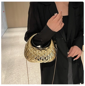 Golden quilted mirror-finish half-moon clutch bag with metallic chain strap worn by model