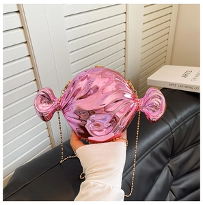 Detail of pink candy-shaped hard shell evening bag with gold chain strap held by hand