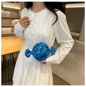 Blue metallic candy-shaped evening clutch bag with gold chain strap on white dress
