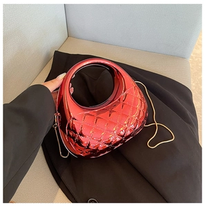 Close-up of red metallic clutch bag featuring quilted pattern and circular handle