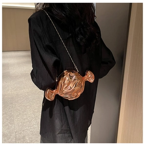 Detail of rose gold candy-shaped evening bag with metallic finish and chain strap
