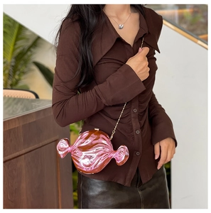 Detail of candy-shaped crossbody bag with metallic rose pink finish and gold chain