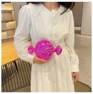 Close-up of a pink candy-shaped evening clutch bag with gold chain on a white dress