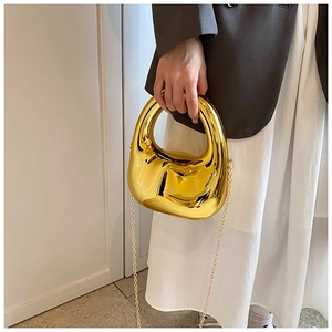 Detalle de un bolso de noche metálico dorado de lujo con acabado de espejo brillante