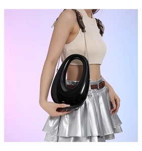 Detalle del bolso de acrílico negro brillante en forma de guijarro con acabado de espejo