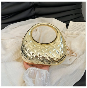 Close-up of gold shell handbag featuring quilted patterns and round metal handle