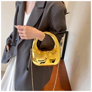 Primer plano de bolso de fiesta metálico dorado pulido con cadena usado por una modelo