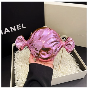 Close-up of pink metallic candy-shaped clutch with gold chain held in hand