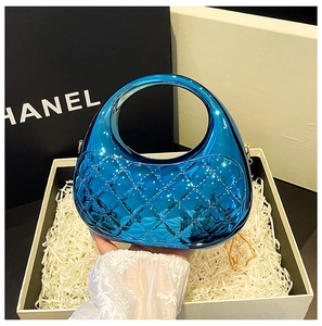 Macro detail of glossy blue acrylic clutch bag with quilted pattern inside a gift box