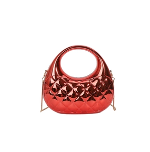 Macro detail of red metallic quilted shell bag with distinct oval cutout and gold chain