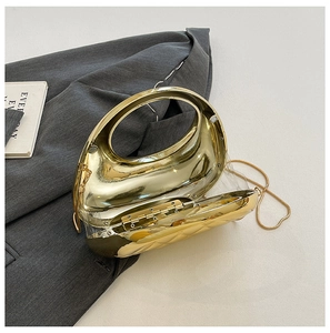 Detail of gold metal handbag with round handle and chain strap on dark blazer