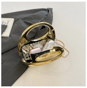 Detailed view of gold oval acrylic clutch showing storage capacity with metallic handle