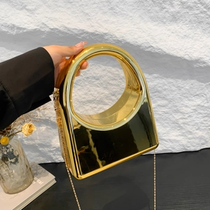 Detail of gold mirror acrylic clutch with geometric circular handle and chain strap