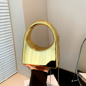 Close-up of golden acrylic evening clutch with semi-circular handle and metallic chain strap