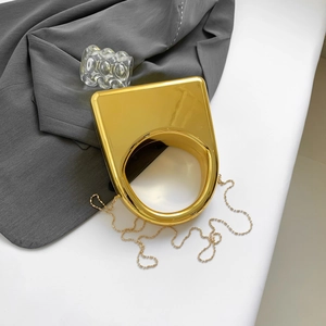 Macro view of geometric gold acrylic evening bag with a metallic bead chain strap