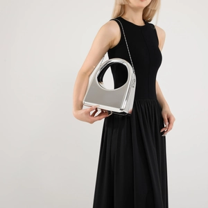 Close-up of futuristic silver mirror finish acrylic evening bag with round cutout handle