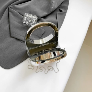 Detail of silver acrylic evening clutch with round cutout handle and bead chain strap
