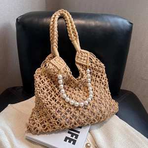 Hollow out woven mesh tote bag with pearl chain detail on a stylish black leather seat