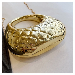 Detail der goldenen Hartschalen-Abendtasche mit Rautenmuster und rundem Griff