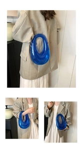 Detail view of transparent blue acrylic bag with gold chain strap on beige blazer