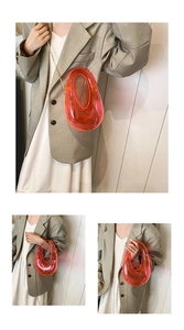 Detailed view of an orange transparent acrylic egg-shaped evening clutch with metal chain