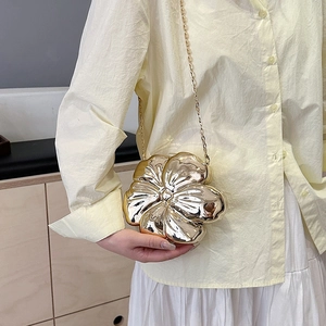 Elegant gold flower evening bag with metallic finish and chain strap on a model