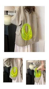 Detail of neon green transparent acrylic clutch bag with gold chain and oval handle