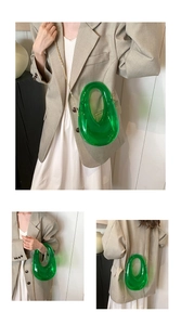 Close-up of emerald green acrylic evening bag with gold chain and pebble shape