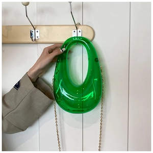Close-up of emerald green translucent acrylic evening clutch with gold chain strap