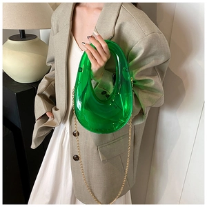 Detail of translucent bright green acrylic clutch with circular handle and gold chain