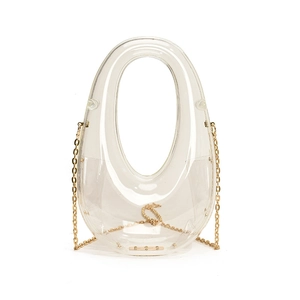 Macro detail of clear acrylic box bag with golden chain strap on white background