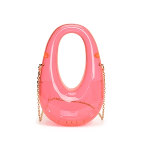 Macro detail of pink translucent acrylic evening bag with gold chain and round handle
