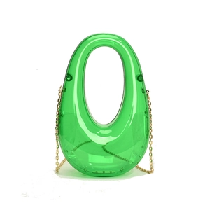 Detail view of oval transparent green acrylic clutch with gold chain strap for evening wear