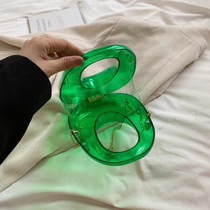 Macro view of transparent green acrylic box bag showing dual round handles and gold chain