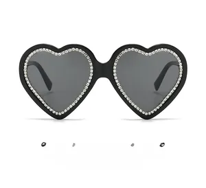 Close-up of heart-shaped sunglasses with sparkling rhinestone frame and dark lenses