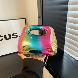Rainbow gradient acrylic handbag with gold chain strap held by hand in natural light shadow