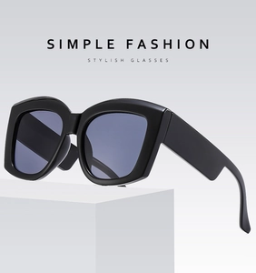 Detail view of bold black square sunglasses with thick temples on a white pedestal